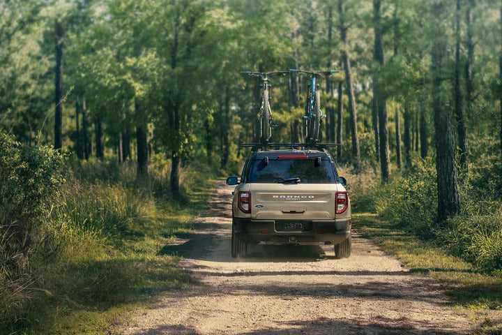 an suv driving on a dirt road with bikes on the top